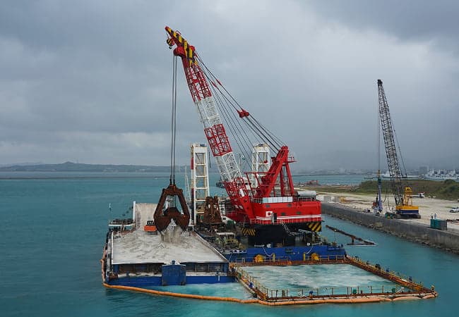 Ein großer Kran hebt ein großes Boot ins Wasser und zeigt beeindruckende Ingenieurskunst in Aktion.